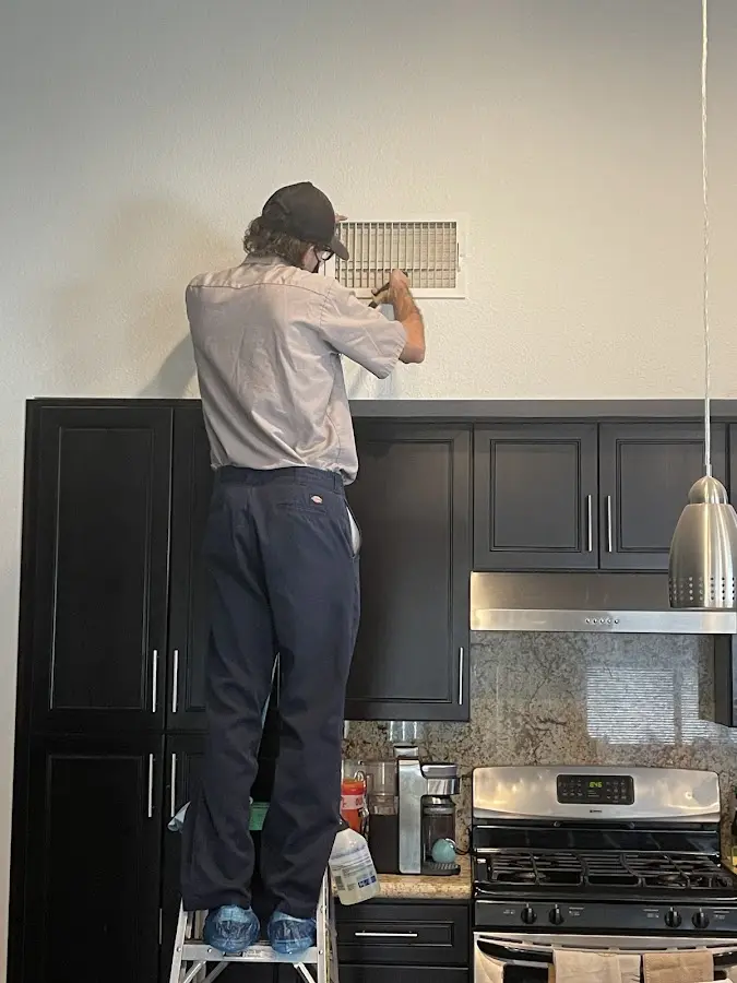 Technician inspecting an air vent during HVAC service in Newington